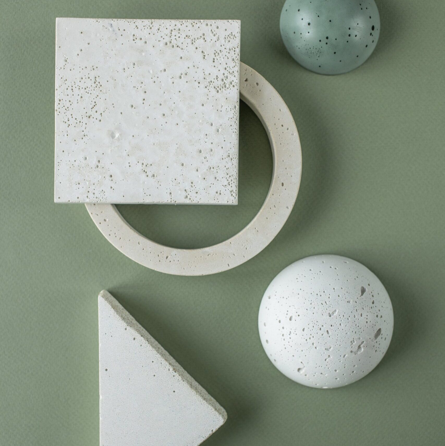 Blocks in different shapes and colors of grey against an olive green background
